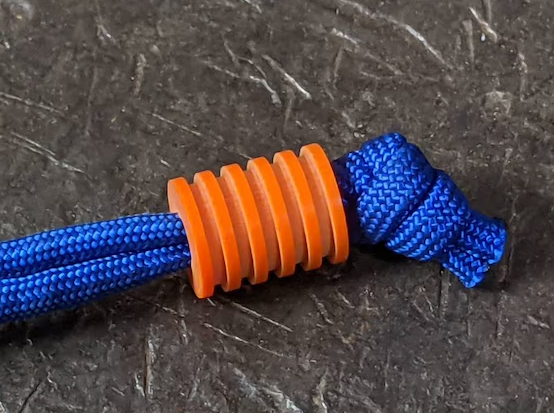 G10 paracord beads in multiple colors threaded on 550 paracord showing layered fiberglass composite construction and bore diameter for EDC knife lanyard applications