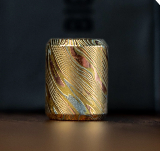 Damascus steel bead attached to knife lanyard on folding EDC knife showing practical everyday carry application