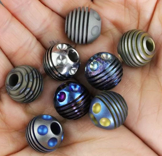 Three titanium beads showing satin, semi-polish, and mirror finishes side by side demonstrating progressive polishing results