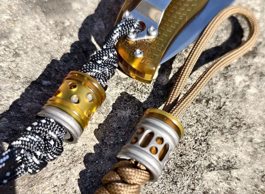 Comparison of aluminum, steel, and brass paracord beads showing weight difference