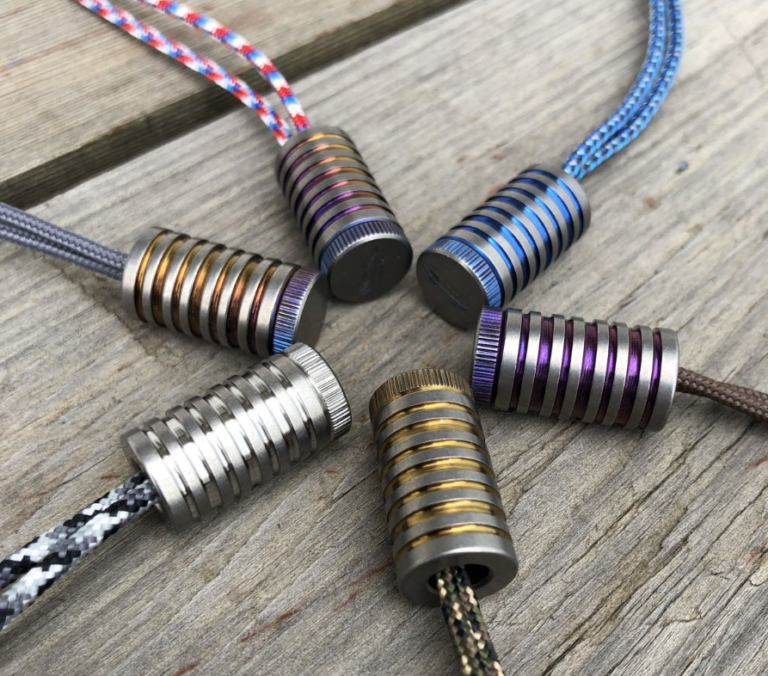 Various titanium paracord beads in different shapes and sizes for customizing gear.