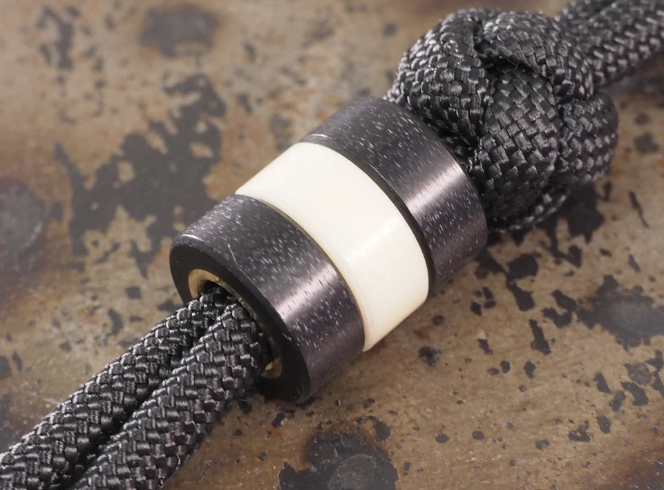 G10 paracord beads on survival bracelet and zipper pull showing silent operation, grip texture, and moisture resistance in outdoor gear applications